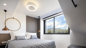 Ein modernes Schlafzimmer mit einem großen Bett, einem Nachttisch, einer Lampe und einem Fenster mit Blick ins Freie.