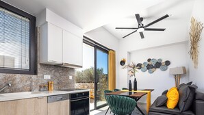 Eine moderne Küche mit Einbauofen, ein Essbereich mit Tisch und Stühlen sowie eine Couch mit Kissen.