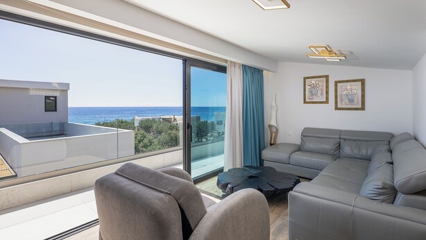 Ein modernes Wohnzimmer mit einem großen Fenster, einem grauen Sofa und einem kleinen Tisch.