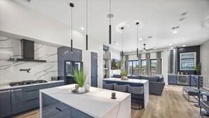 A modern kitchen with marble countertops, a central island, and pendant lighting. - Downtown Hanson- New Constructed 4 level home in East Downtown Houston (Houston)