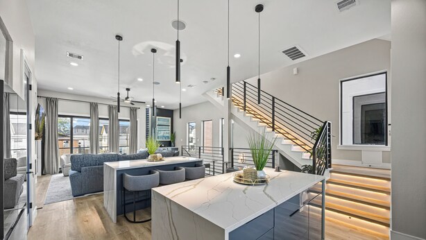 A modern kitchen with a marble island, a staircase, and a dining area with a sofa. - Downtown Hanson- New Constructed 4 level home in East Downtown Houston (Houston)