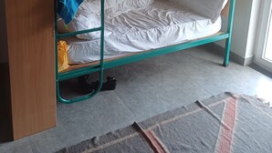 Habitació amb un llit superposat, escriptori, cadira, finestra i porta.