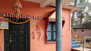 Entrada d'un edifici amb una porta negra i ornamentada, un calendari, un mural a la paret i una escala.