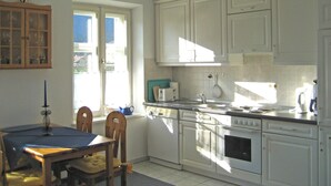 Een keuken met witte kastjes, een fornuis en een raam.
