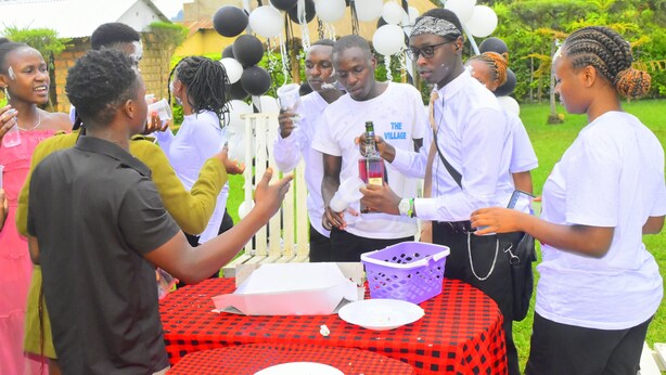 A group of people at an outdoor event with a table, balloons, and a building in the background. - The Cambrian Village Hotel and Resort (Nyamira)