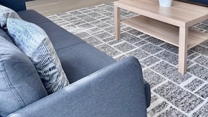 Ein modernes Wohnzimmer mit Flachbildfernseher, eingebautem Kamin, einer Couch und einem Couchtisch.