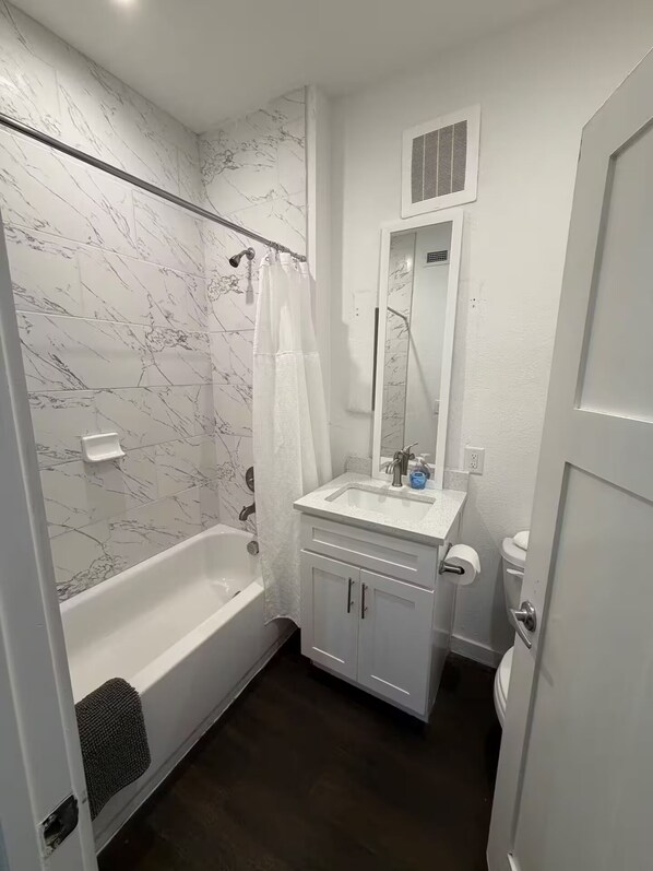 A bathroom with a bathtub, a sink, a toilet, and a shower curtain. - Chill 1x1 Apt. in West Campus! (Austin)