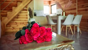Un intérieur en bois avec une table ornée de roses rouges, une cuisine en arrière-plan et un coin repas avec des chaises.