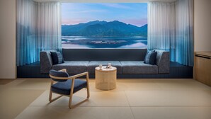 A modern room with a sofa facing a large window overlooking a body of water and mountains. - Hoshino Resorts KAI Miyajima (Hatsukaichi)
