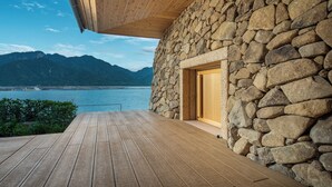 A stone building with a wooden deck and a view of a lake and mountains. - Hoshino Resorts KAI Miyajima (Hatsukaichi)