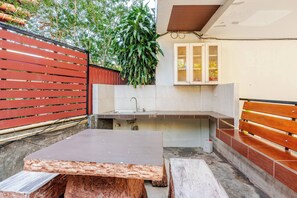 A compact kitchen with a sink, wooden bench, and cabinets. - Cozy 1-bedroom Apartment With Kitchen and Bathroom Near Kata Beach (Karon)