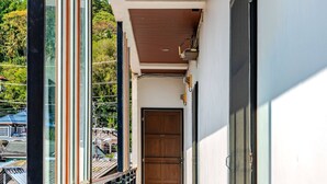 Un pasillo con piso de baldosas, una puerta de madera y una barandilla de cristal con vistas.