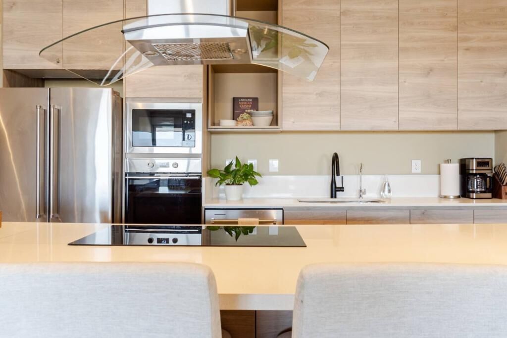 A modern kitchen with stainless steel appliances, a glass island, and wooden cabinetry.