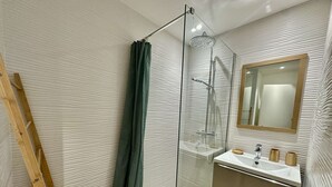 A modern bathroom with a glass shower enclosure, a wooden ladder, a sink with a mirror, and a wooden stool. - IN THE HEART OF THE CITY CENTER, ONE BEDROOM APARTMENT FOR 4 PEOPLE (STE MAXIME)
