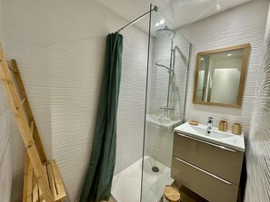 A modern bathroom with a glass shower enclosure, a wooden ladder, a sink with a mirror, and a wooden stool. - IN THE HEART OF THE CITY CENTER, ONE BEDROOM APARTMENT FOR 4 PEOPLE (STE MAXIME)