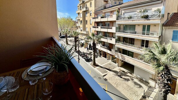 A balcony with a table set for dining, overlooking a residential area with multi-story buildings and palm trees. - IN THE HEART OF THE CITY CENTER, ONE BEDROOM APARTMENT FOR 4 PEOPLE (STE MAXIME)