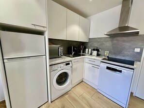 A compact kitchen with a built-in washer, dishwasher, and microwave. - IN THE HEART OF THE CITY CENTER, ONE BEDROOM APARTMENT FOR 4 PEOPLE (STE MAXIME)