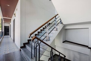 A modern interior with a staircase, a hallway, and a door at the end. - VK Living Room 20 min Walk to Kata Beach #302 (Karon)