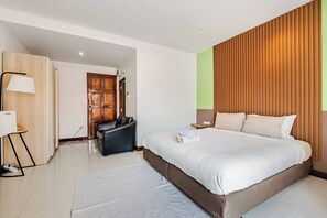 Ein modernes Hotelzimmer mit einem großen Bett, einem Schreibtisch mit Lampe, einem Kleiderschrank und einer Wandpaneele aus Holz.