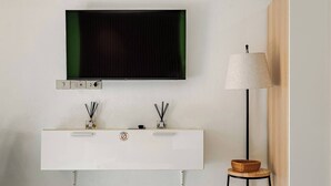 Ein modernes Badezimmer mit montiertem Fernseher, einem weißen Waschtisch und einer Stehlampe.