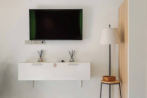 A modern bathroom with a mounted TV, a white vanity, and a floor lamp. - VK Living Room 20 min Walk to Kata Beach #302 (Karon)