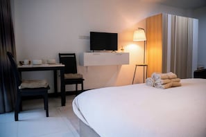 A hotel room with a bed, a desk with a television, a chair, and a lamp. - VK Living Room 20 min Walk to Kata Beach #302 (Karon)