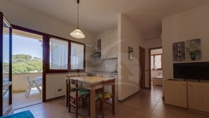 Une cuisine moderne avec un coin repas, un téléviseur et un balcon offrant une vue sur les arbres.