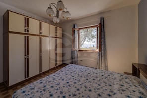 A bedroom with a bed, wardrobe, window, and curtains.