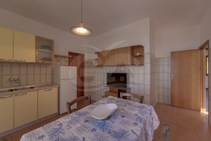 A compact kitchen with a dining area, a refrigerator, a microwave, and a table with a chair.