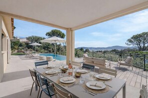 An outdoor dining area with a view of a swimming pool and mountains. - Magnificent villa with a pool and panoramic sea views, 6 persons – Gulf of Saint-Tropez (GRIMAUD)
