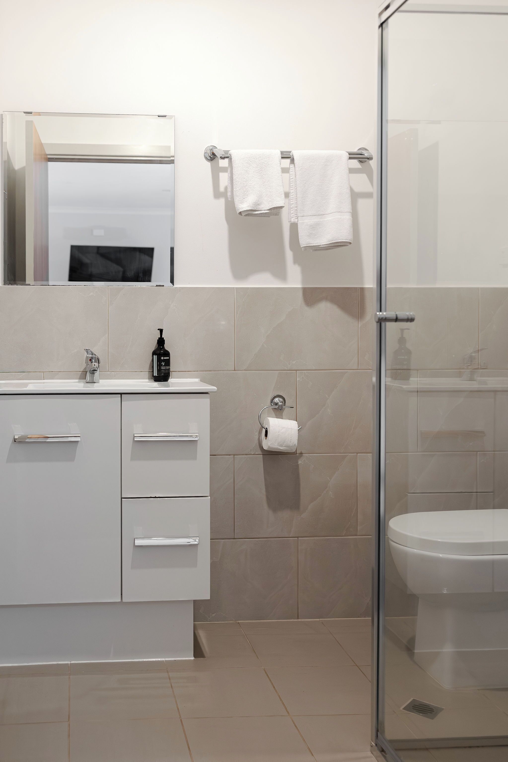 A modern bathroom with a glass shower enclosure, a white sink with a mirror, and a toilet.
