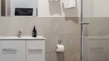 A modern bathroom with a glass shower enclosure, a white sink with a mirror, and a toilet.