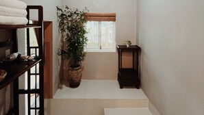 A narrow hallway with a wooden staircase, a potted plant, a small table, and a window with a view. - An Nhiên Farm dormitory with bunk beds (Pleiku)