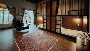 A room with bunk beds, a circular hanging chair, a patterned rug, and a large window. - An Nhiên Farm dormitory with bunk beds (Pleiku)