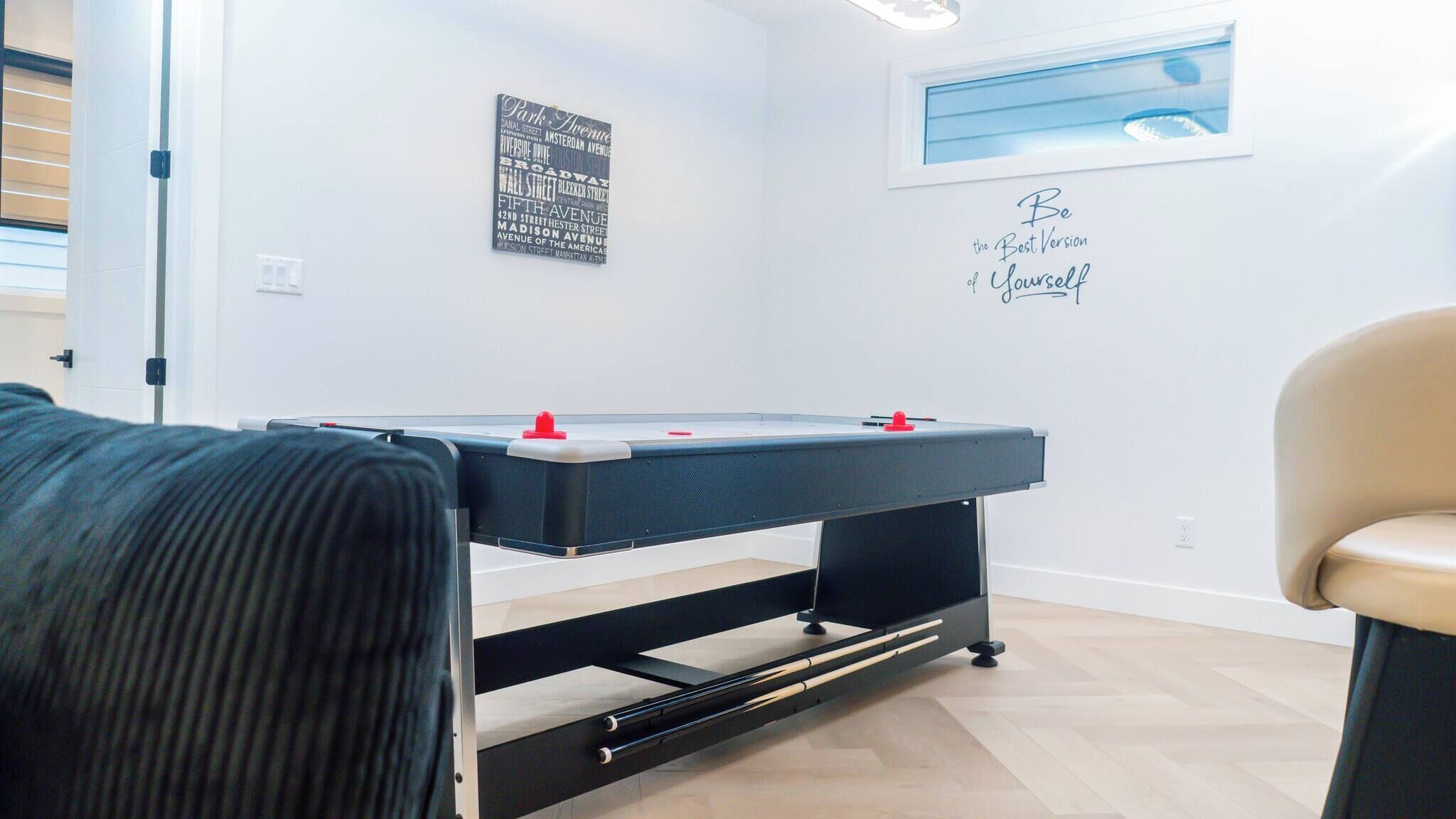 A room with a foosball table, a wall with a motivational quote, and a window with a view.