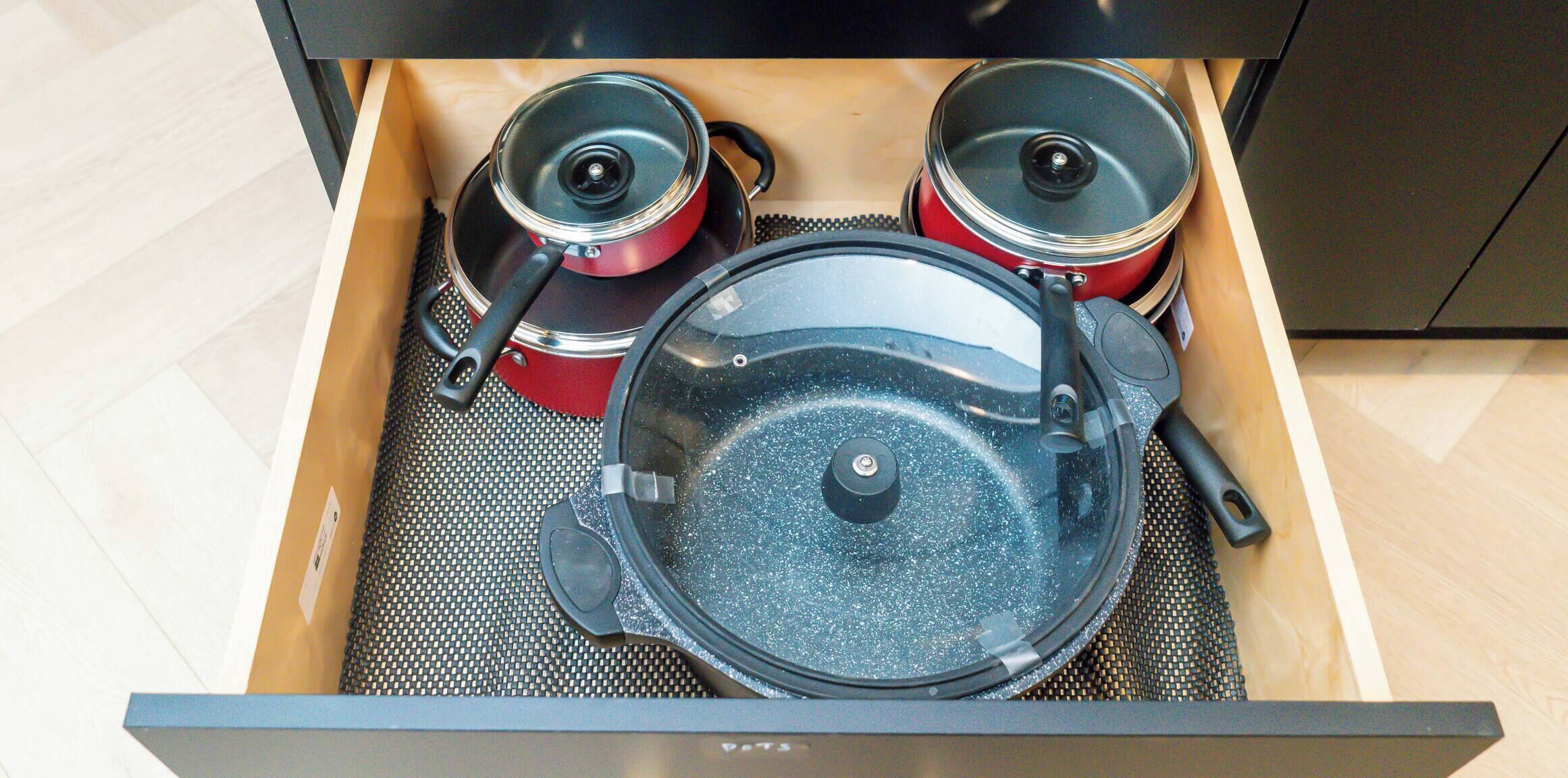 A drawer with two red pots and a large blue pan.