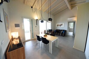 Ein geräumiger Wohnbereich mit Esstisch, Stühlen, einer Couch und einem Fernseher.
