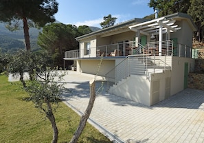 Ein zweigeschossiges Gebäude mit Balkon, Treppe und Blick auf die umliegende Landschaft.