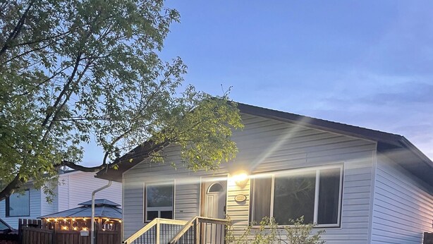 A residential house with a front porch, a small garden, and a wooden fence. - 3 bedroom main level home away from Home! Pet friendly with fenced backyard! (Grande Prairie)