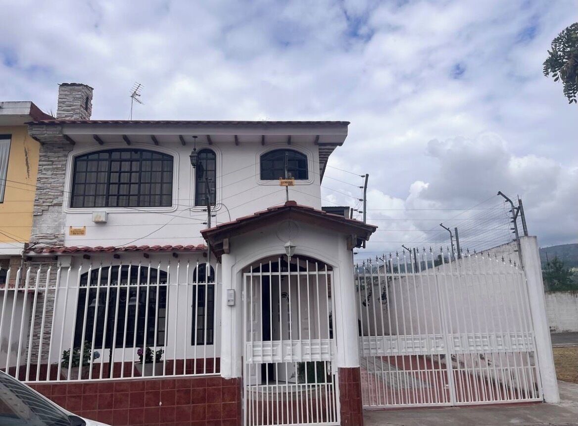 A two-story house with a gated entrance, a chimney, and a satellite dish.