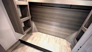 Une pièce dotée d’un plafond en pente, d’étagères intégrées et d’un plancher en bois.