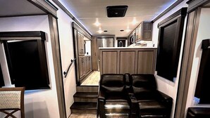 Un intérieur de camping-car compact comprenant un coin cuisine, un espace salon avec deux canapés en cuir et une petite table à manger.