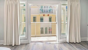 Una habitació amb una gran porta corredissa de vidre que dona a un balcó amb barana blanca.