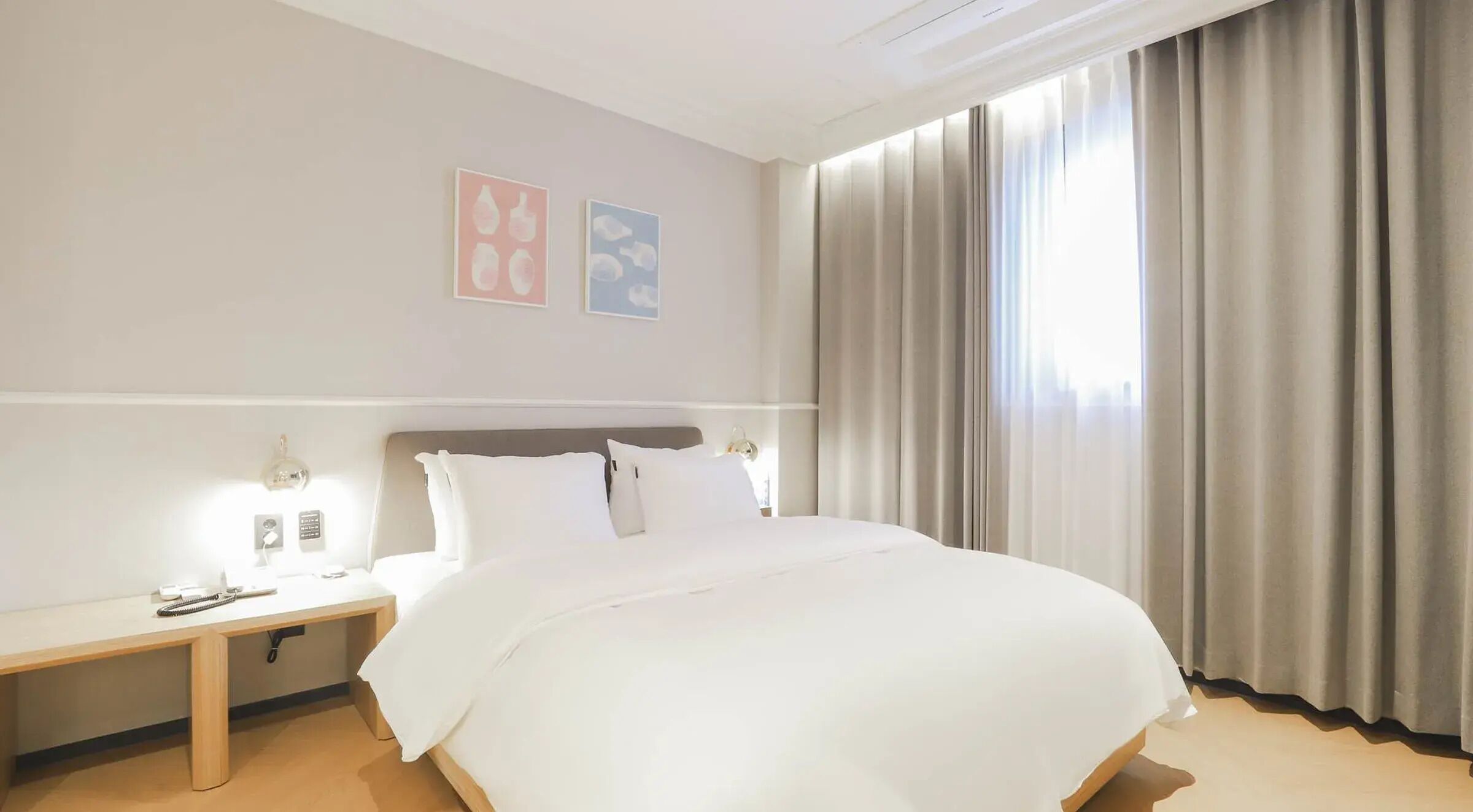 A hotel room with a large bed, bedside tables, a nightstand, and a window with curtains.
