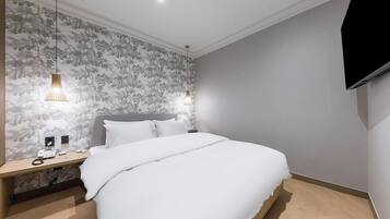 A modern hotel room with a large bed, two bedside tables, a wall-mounted TV, and a patterned wallpaper.