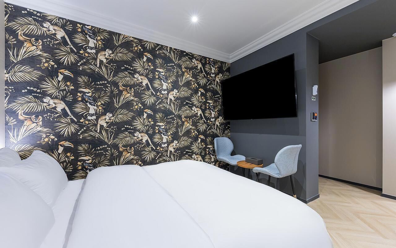 Una habitación de hotel con cama, televisión, una mesita y una silla.