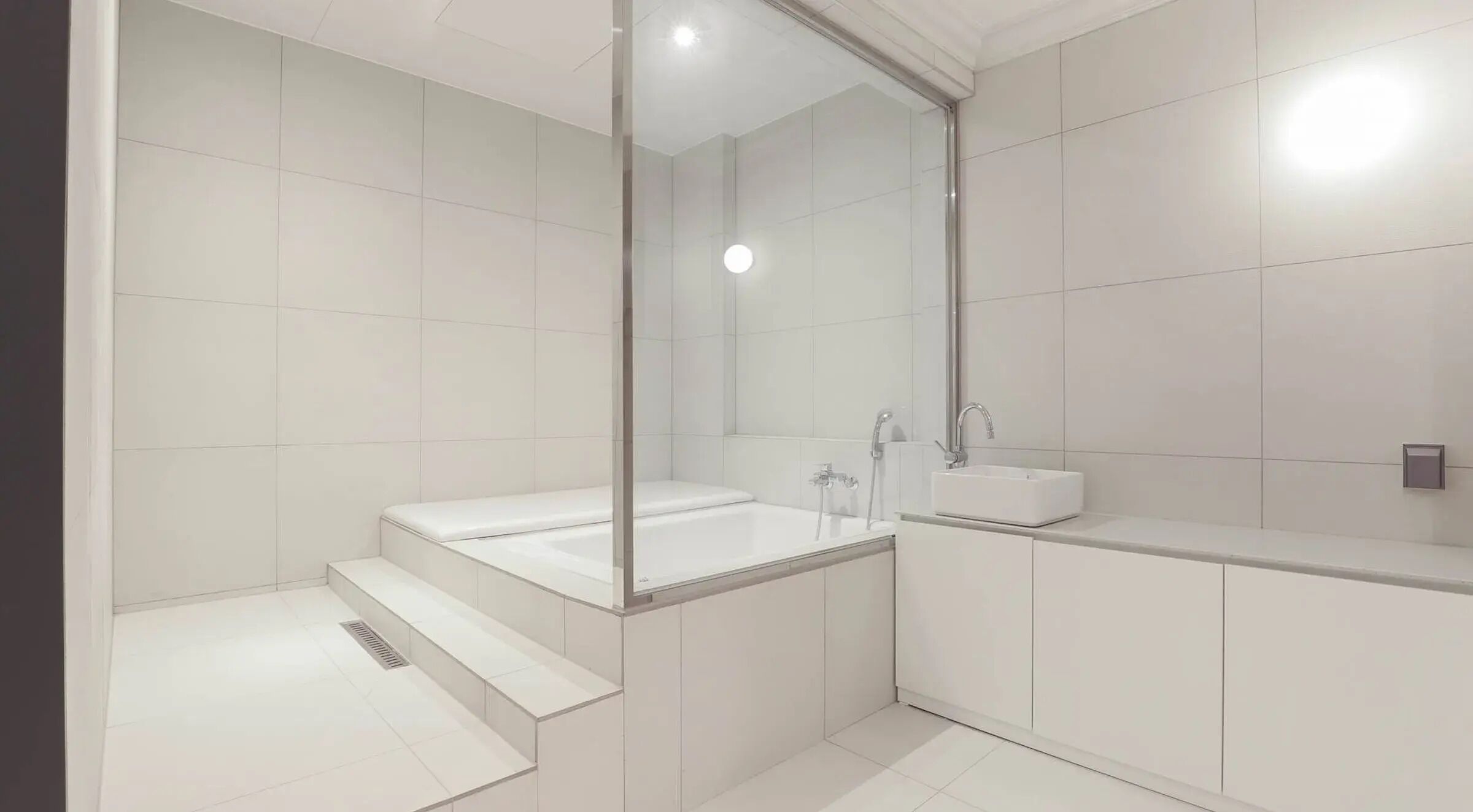 Un baño moderno con ducha de vidrio, una bañera independiente y un tocador con lavabo.