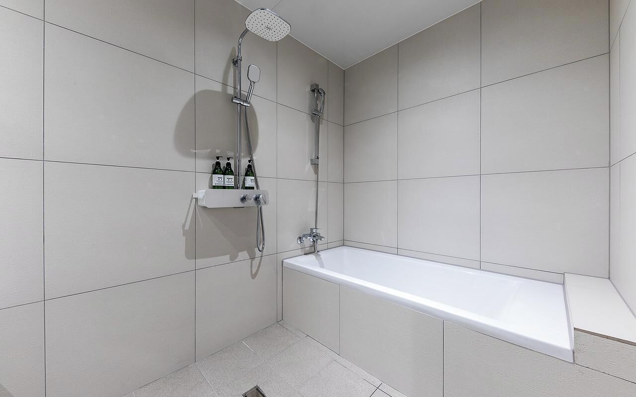 Un baño moderno con bañera, ducha y un estante con artículos de aseo.