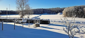 A snow-covered outdoor area with a fence, benches, and a trash bin. - Welcome to Lillstugan (Jämshög)
