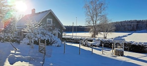 A house with a snow-covered roof, a fenced yard, and a bench. - Welcome to Lillstugan (Jämshög)